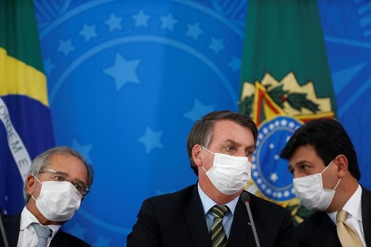 El presidente de Brasil, Jair Bolsonaro, el ministro de Salud, Luiz Henrique Mandetta, y el ministro de Economía, Paulo Guedes, visten mascarillas protectoras mientras asisten a una conferencia de prensa para anunciar medidas para contener el avance del brote de coronavirus, en Brasilia. 18 de marzo de 2020. REUTERS/Adriano Machado.