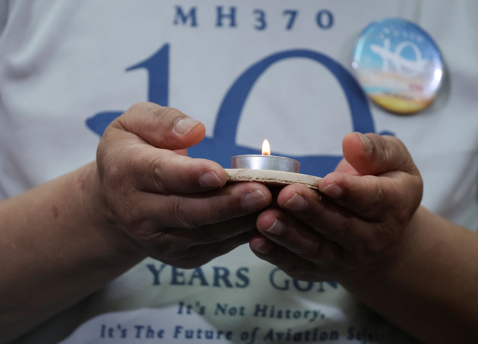 Un familiar del vuelo MH370 desaparecido de Malaysia Airlines sostiene una vela durante un evento conmemorativo que conmemora el décimo aniversario de su desaparición, en Subang Jaya, Malasia. REUTERS/Hasnoor Hussain