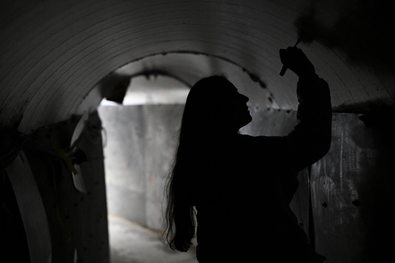 Una mujer escribe un mensaje en un túnel simbólico construido en Tel Aviv para reproducir las condiciones en las que sobreviven los rehenes israelíes en Gaza (REUTERS/Dylan Martinez/Archivo)